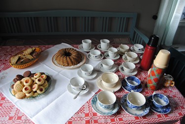 En drös kaffekoppar uppställda tillsammans med kakor och fikabröd.